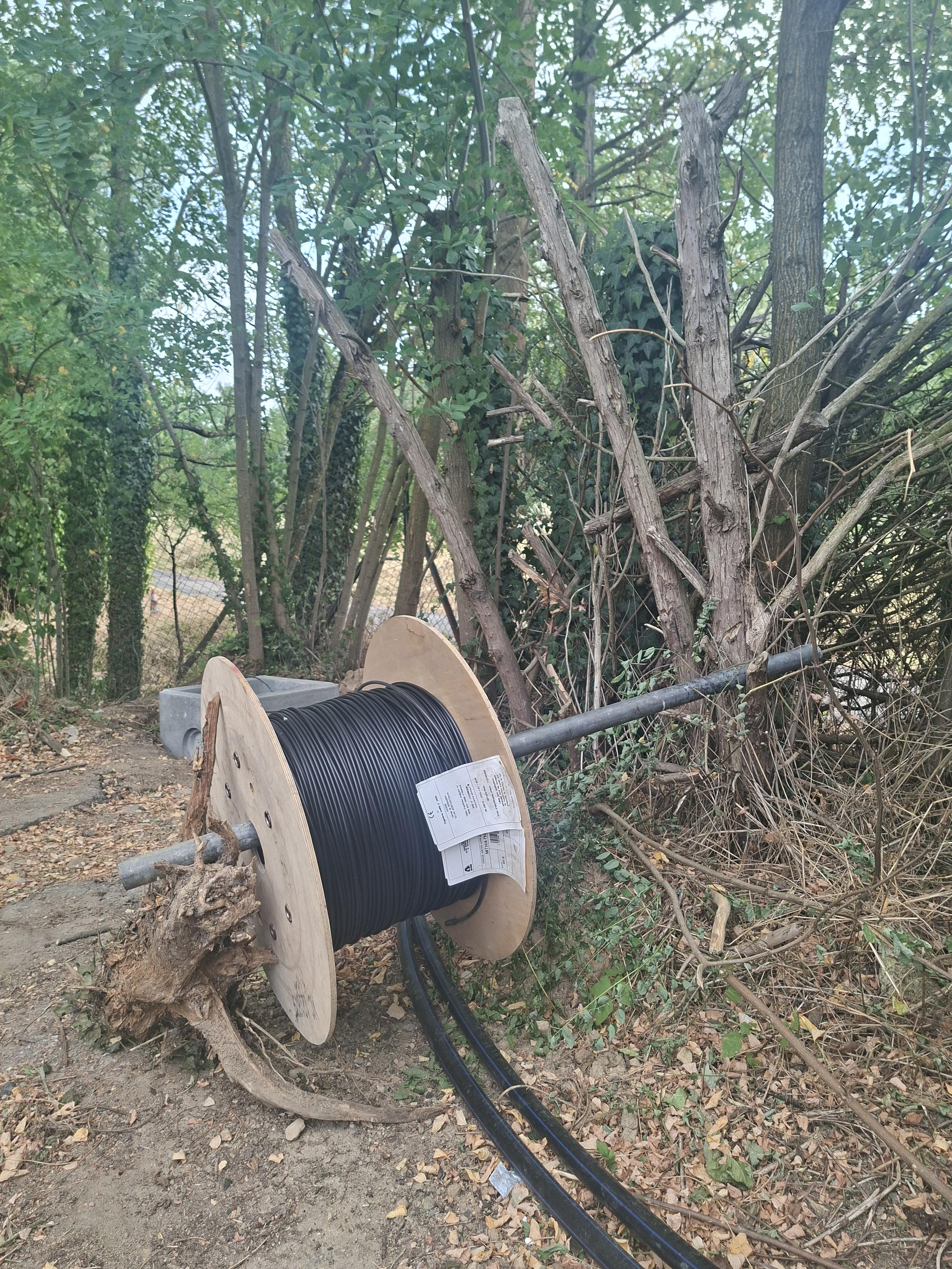 Photo d'un touret de fibre optique sur une barre en métal coincé dans un arbre et un morceau de bois mort, pour lui permettre de se dérouler facilement. 
